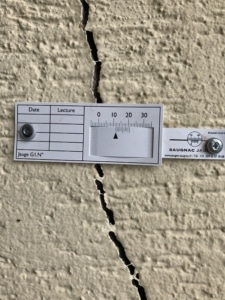 Pose d'une jauge pour mesurer l'évolution de la fissure sur le mur de la maison