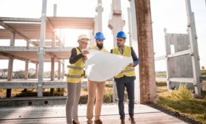 Professionnels du bâtiment consultant des plans sur un chantier d’immobilier d’entreprise