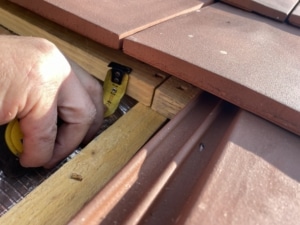 Expert contrôlant l’espacement des liteaux sous une toiture en tuiles